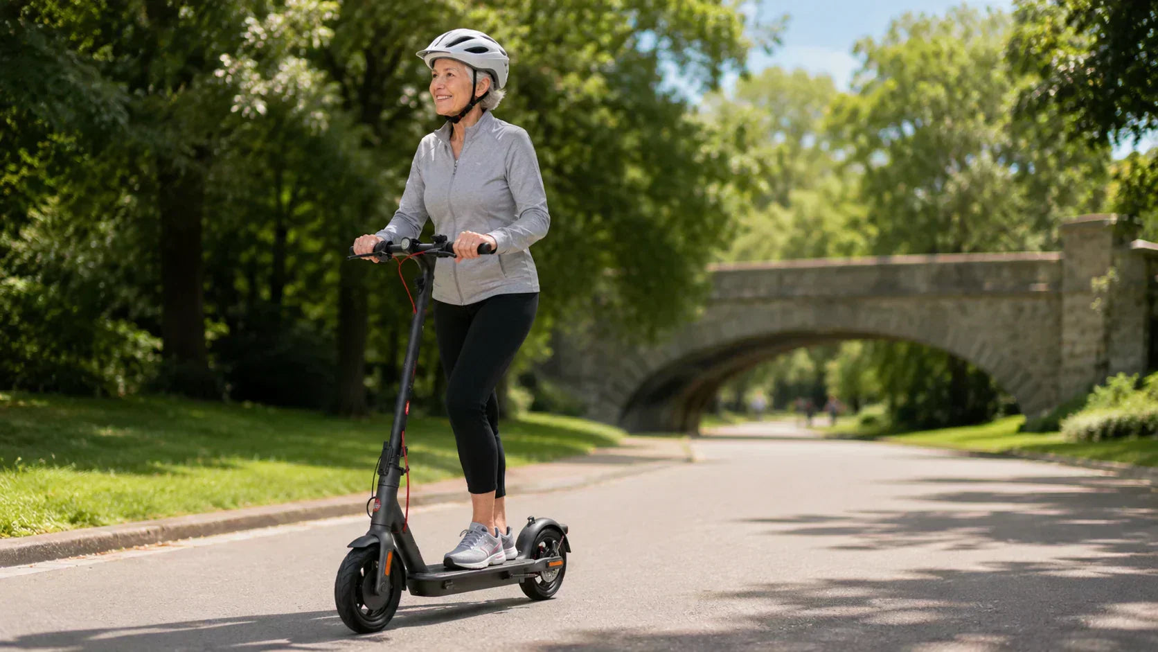 Active senior woman riding an electric scooter on a paved park road